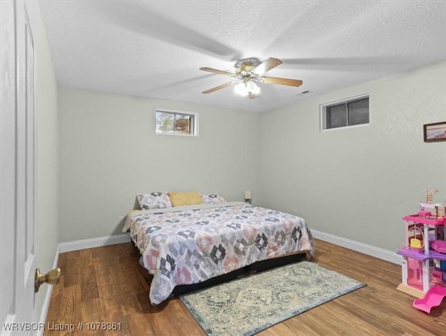 bedroom featuring ceiling fan, wood-type flooring, and a textured ceiling