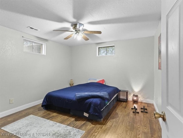 bedroom featuring dark hardwood / wood-style flooring, a textured ceiling, and ceiling fan