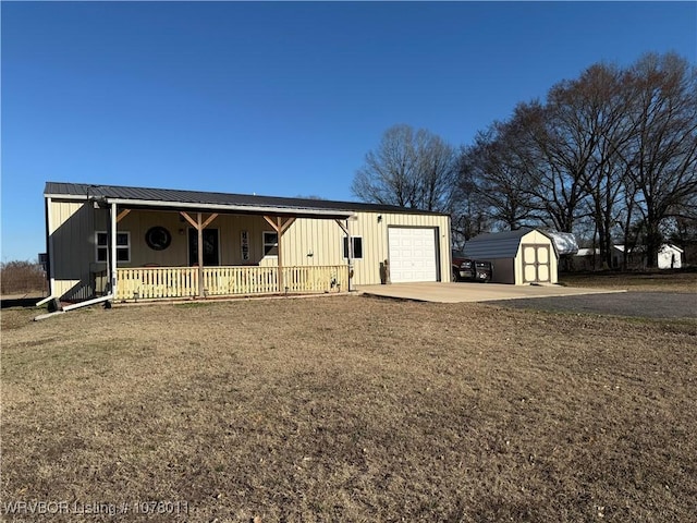 view of front of property with metal roof, a porch, an outdoor structure, driveway, and a shed