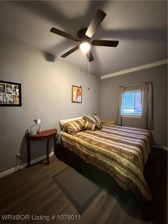 bedroom with dark hardwood / wood-style floors, vaulted ceiling, and ceiling fan