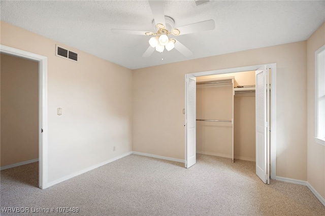 unfurnished bedroom featuring ceiling fan, light colored carpet, a textured ceiling, and a closet