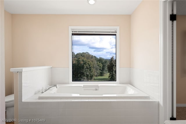 bathroom featuring toilet and tiled tub