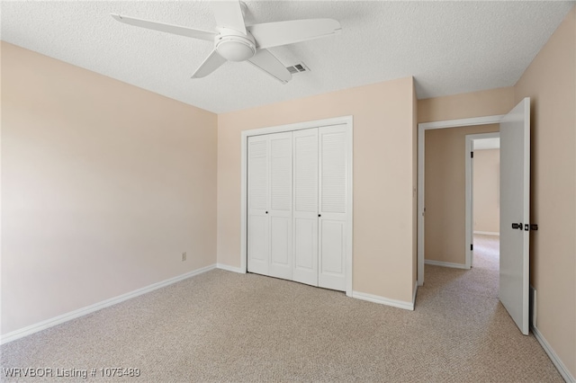 unfurnished bedroom with ceiling fan, a closet, light carpet, and a textured ceiling