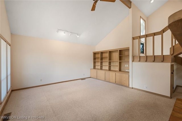 unfurnished living room featuring light colored carpet, high vaulted ceiling, and track lighting