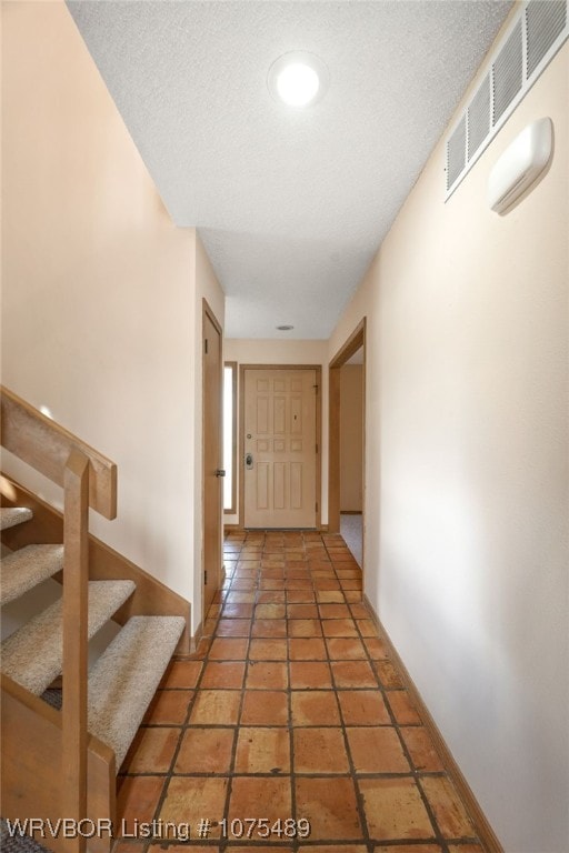 hallway featuring a textured ceiling and dark tile patterned floors