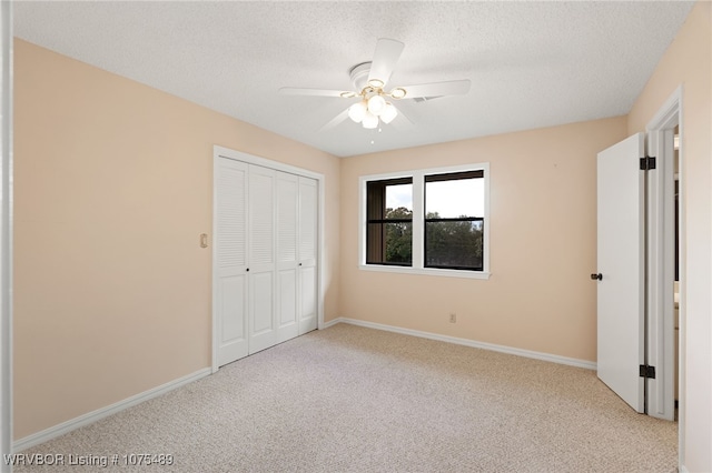 unfurnished bedroom with ceiling fan, a closet, light carpet, and a textured ceiling