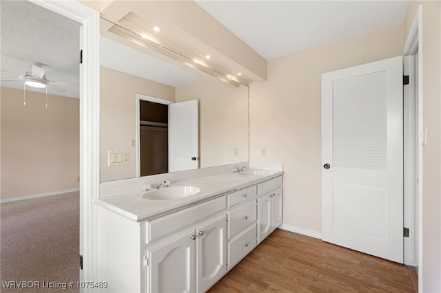 bathroom with wood-type flooring, vanity, a textured ceiling, and ceiling fan