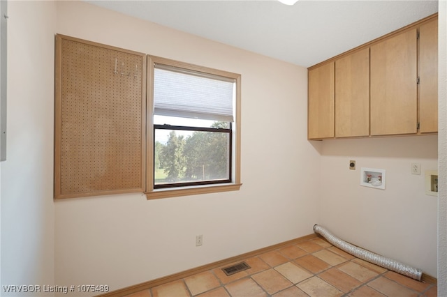 laundry area with hookup for an electric dryer, cabinets, and light tile patterned flooring