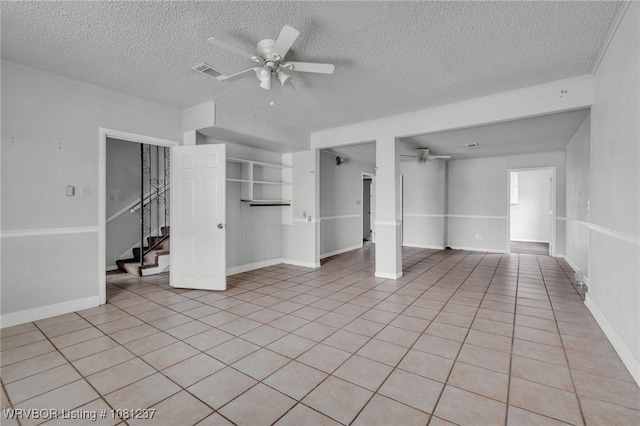 2101 N I St, Fort Smith, AR 72901 - unfurnished living room featuring a ceiling fan, a textured ceiling, baseboards, light tile patterned floors, and stairs