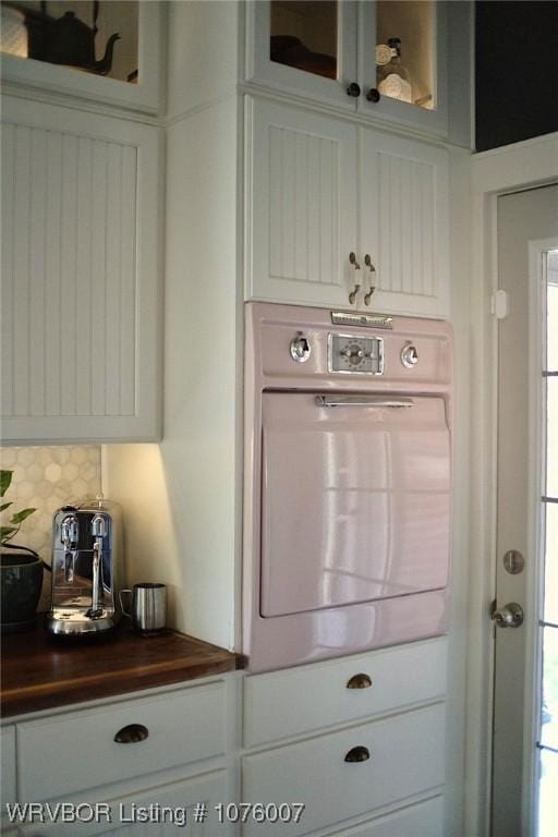 interior space with washer / dryer, white cabinetry, and tasteful backsplash