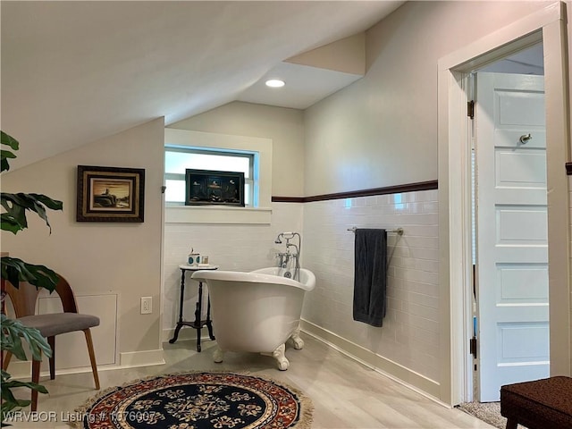 bathroom featuring a tub to relax in and lofted ceiling