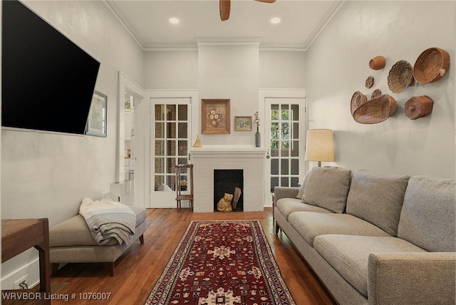 living room with a fireplace, dark hardwood / wood-style flooring, ceiling fan, and crown molding