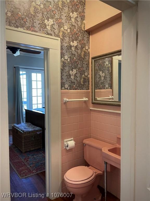 bathroom featuring toilet, wood-type flooring, and tile walls