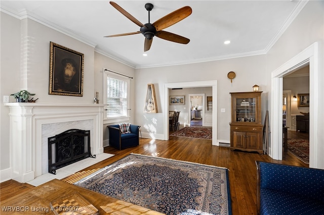 living room with a fireplace, crown molding, ceiling fan, and dark wood-type flooring