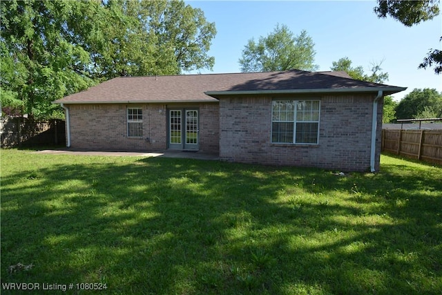 back of property with a yard, a patio, brick siding, and a fenced backyard