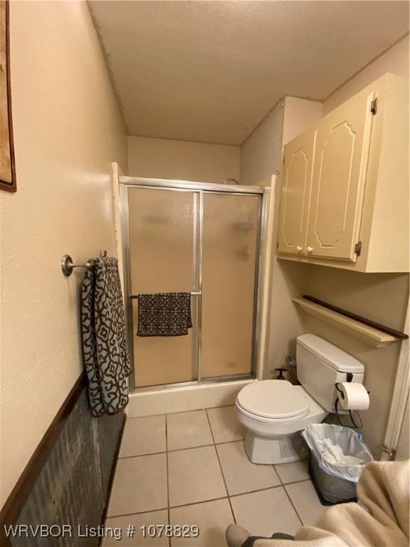 bathroom featuring toilet, a shower with door, and tile patterned flooring