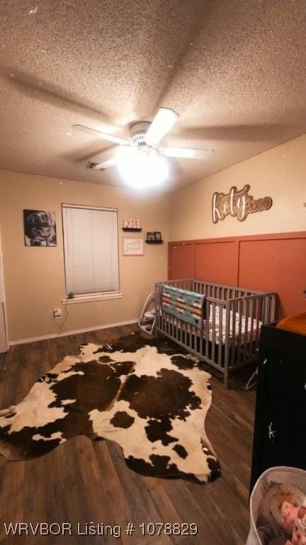 bedroom with ceiling fan, dark hardwood / wood-style floors, and a textured ceiling