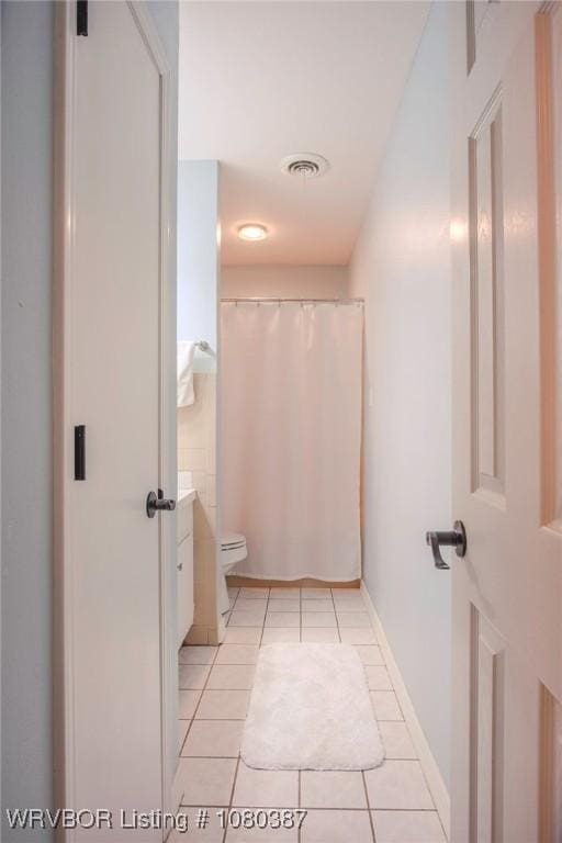 bathroom featuring tile patterned floors, a shower with curtain, toilet, baseboards, and visible vents