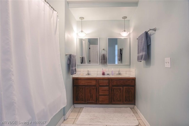 full bath with baseboards, tile patterned floors, a sink, and double vanity
