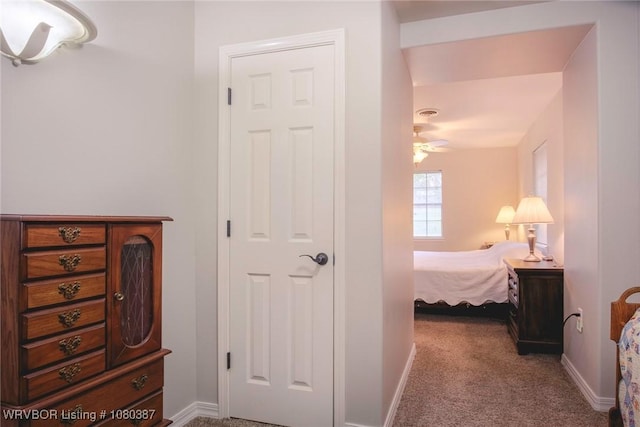 corridor featuring baseboards and carpet flooring