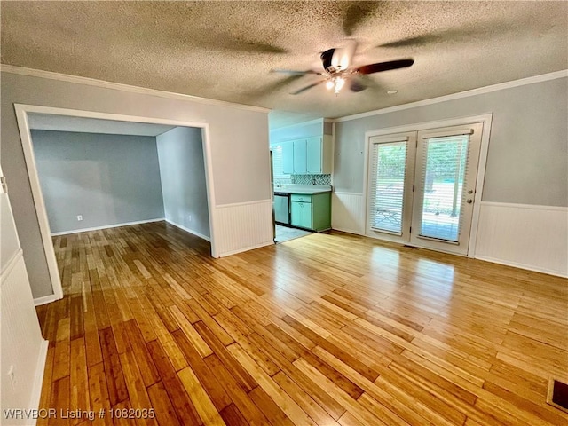 2119 55th Pl, Fort Smith, AR 72904 - unfurnished living room with crown molding, light wood-style flooring, ceiling fan, a textured ceiling, and a wainscoted wall