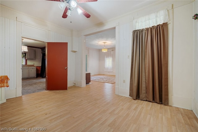 spare room featuring light wood-type flooring, ceiling fan, and crown molding