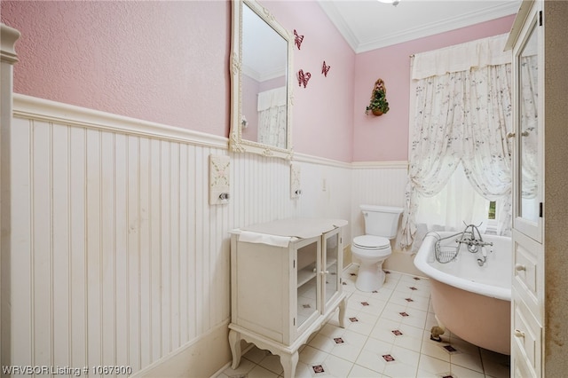 bathroom with tile patterned floors, toilet, ornamental molding, and a tub