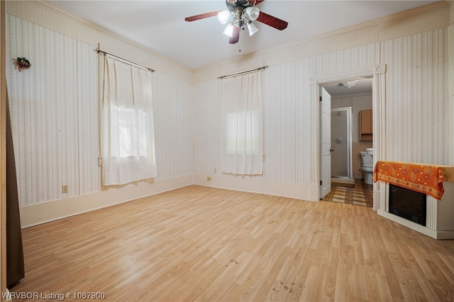 unfurnished living room featuring wood-type flooring, ceiling fan, and ornamental molding