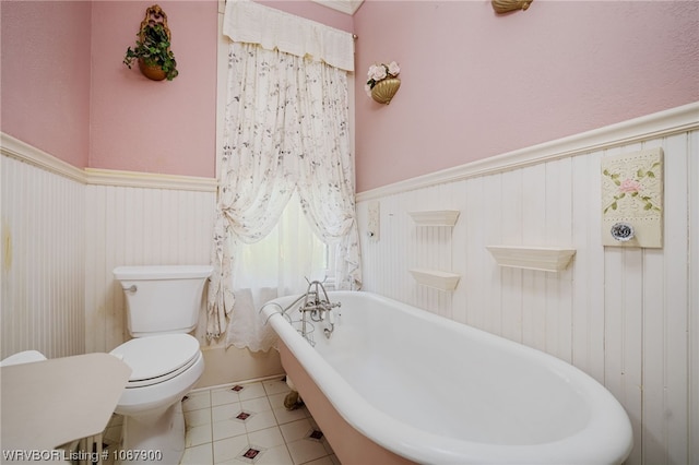 bathroom featuring tile patterned flooring, a tub to relax in, and toilet