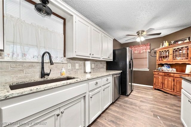 kitchen featuring light wood-style flooring, a ceiling fan, a sink, white cabinetry, and appliances with stainless steel finishes