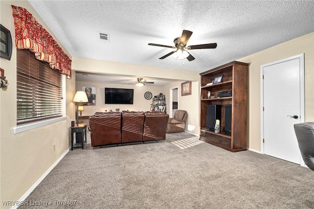 living room featuring baseboards, visible vents, ceiling fan, a textured ceiling, and carpet flooring