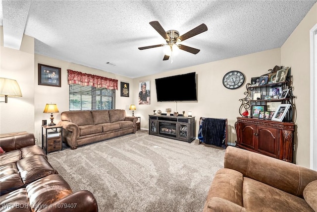 living room with visible vents, carpet, ceiling fan, and a textured ceiling