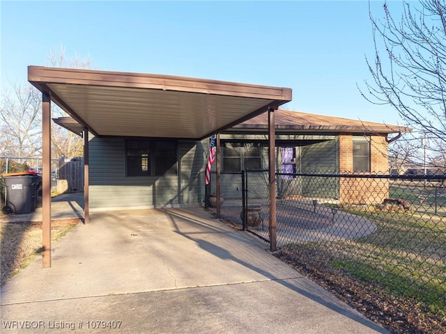 exterior space with an attached carport, concrete driveway, and fence