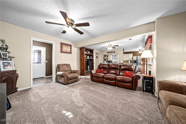 carpeted living room with a ceiling fan, baseboards, and a textured ceiling