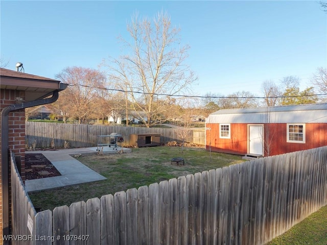 view of yard featuring a patio area, an outbuilding, a fenced backyard, and an outdoor fire pit