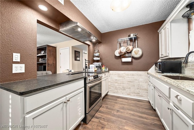 kitchen with dark wood finished floors, a sink, electric stove, a textured ceiling, and wall chimney range hood