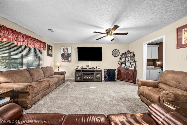 living area featuring visible vents, carpet flooring, a textured ceiling, and a ceiling fan