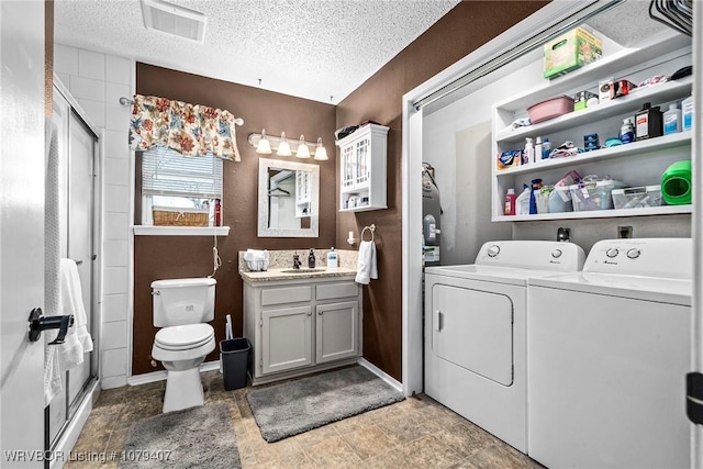 interior space featuring visible vents, toilet, a stall shower, washer and clothes dryer, and a textured ceiling