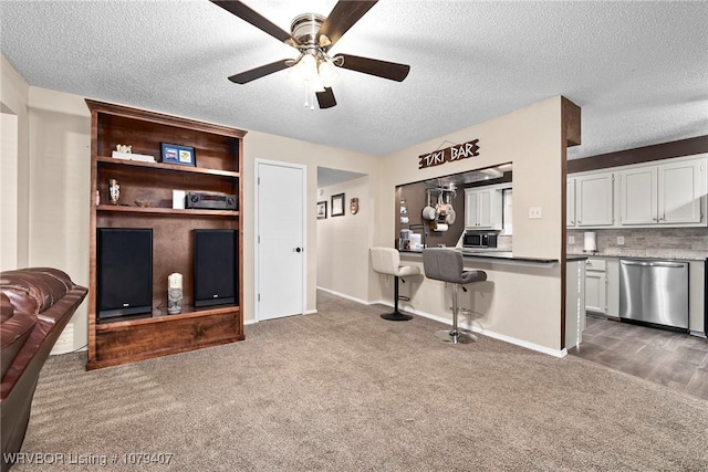 living area with baseboards, carpet floors, a textured ceiling, and a ceiling fan