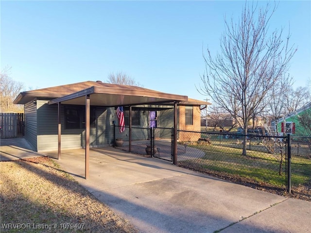 exterior space featuring an attached carport, concrete driveway, and fence