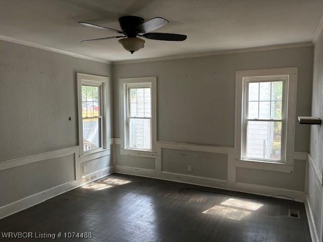 empty room with ceiling fan, plenty of natural light, and crown molding