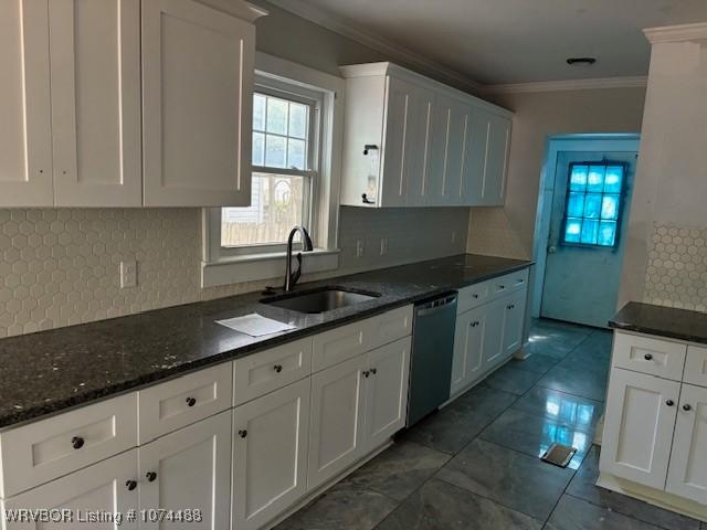 kitchen featuring backsplash, white cabinetry, stainless steel dishwasher, and sink