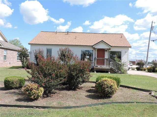 view of front of home featuring a front lawn and roof with shingles