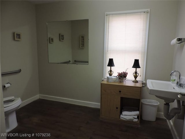 half bathroom with toilet, baseboards, and wood finished floors