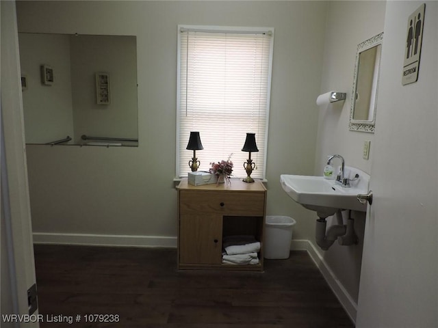 half bath with a sink, baseboards, and wood finished floors