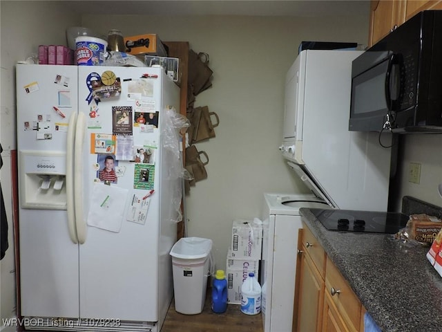 kitchen featuring white refrigerator with ice dispenser, black microwave, dark stone countertops, and wood finished floors