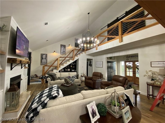 living room with hardwood / wood-style flooring, a large fireplace, lofted ceiling, and a chandelier