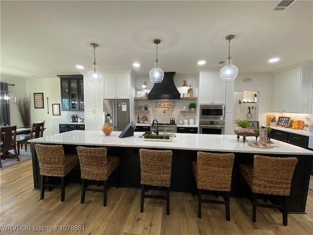 kitchen with premium range hood, appliances with stainless steel finishes, a large island, and a kitchen breakfast bar