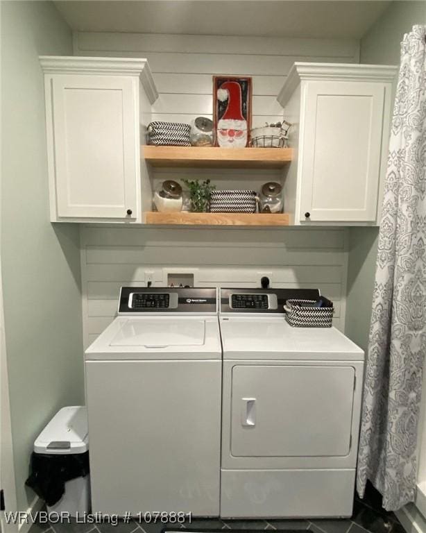 clothes washing area featuring cabinets and separate washer and dryer