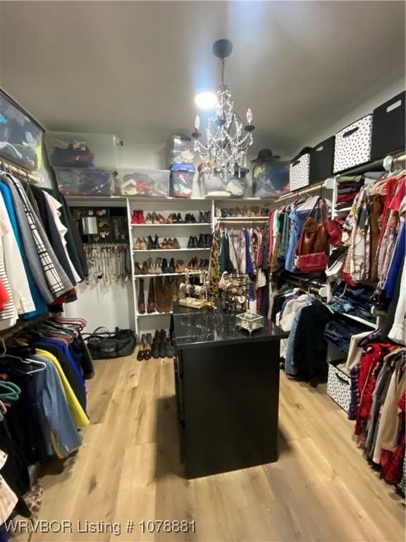 walk in closet with an inviting chandelier and hardwood / wood-style flooring